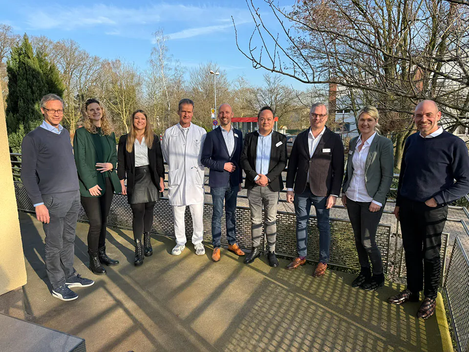 Die Geschäftsleitung und das Team des Lukas-Krankenhauses Gronau in Westfalen stehen im Freien bei sonnigem Wetter und genießen den Neujahrsempfang