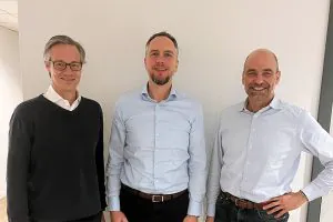 Aktuelles – Artikel 2 CEO Martin Stein, CFO Dr. Ingo Böhner und der neue COO Dr. Kristian Koch stehen lächelnd nebeneinander vor einer weißen Wand
